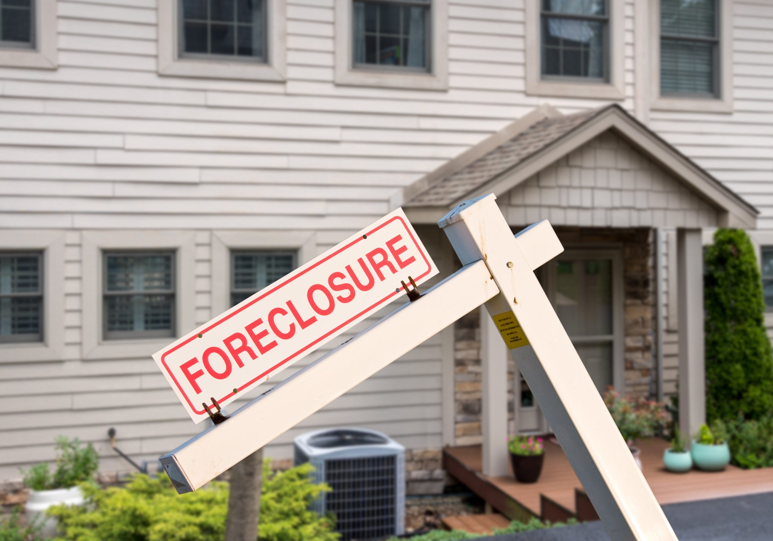 Mockup of a foreclosure sign in front of a modern townhome or townhouse to illustrate recession fears due to coronavirus